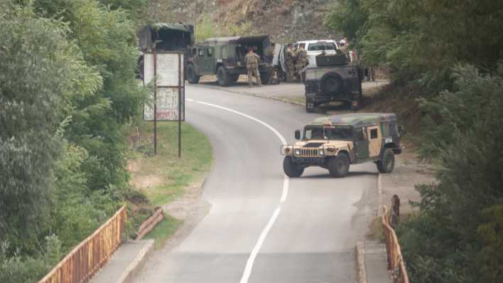 Mitglieder der NATO-geführten Friedensmission im Kosovo errichten einen Kontrollpunkt auf einer Straße, die zum Kloster der Stadt Banjska führt (Bild: picture alliance / Visar Kryeziu)