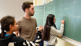 Lehramtsstudent arbeitet mit Schülerinnen und Schülern
