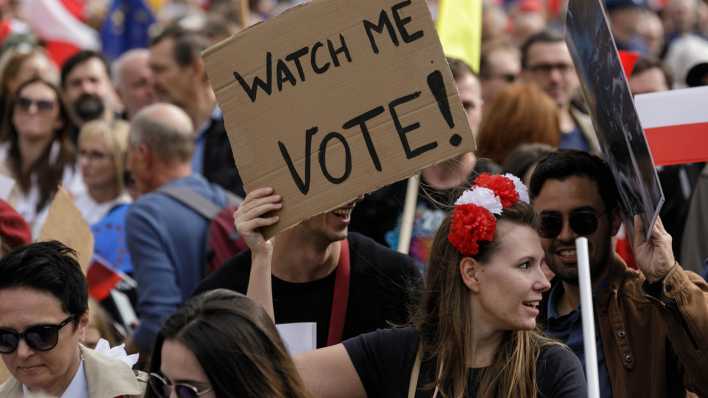 Eine Frau hält währnde einer Demo in Polen ein Schild in der Hand mit der Aufschrift 'Watch me Vote!' (Sieh mich an Wähle!) (Bild: picture alliance / ZUMAPRESS.com | Volha Shukaila)