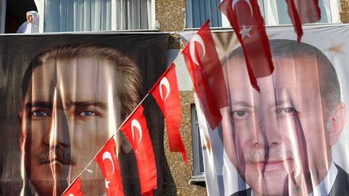 Eine Frau blickt aus einem Fenster hinter einem Banner des türkischen Staatsgründers Atatürk (l) und des türkischen Präsidenten Erdogan