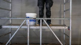 Ein Handwerker auf einem Baugeruest auf einer Baustelle in Berlin