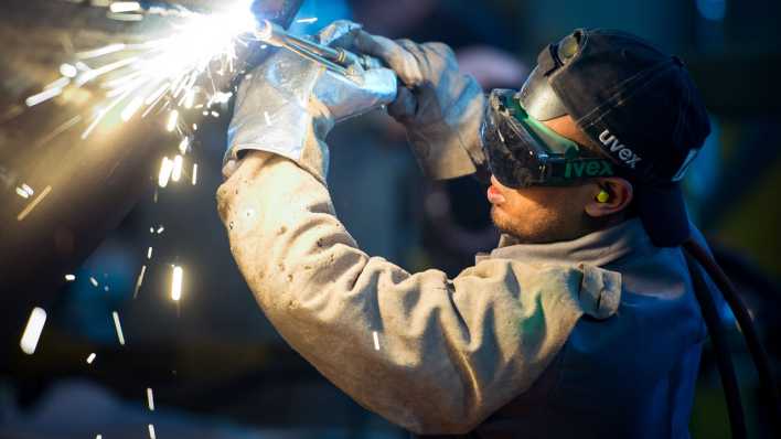 Ein Mann aus Somalia arbeitet in einer Firma an einem Stahlsegment.
