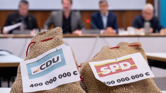 Zwei Säckchen, auf denen "CDU 400 000 000 €" und "SPD 400 000 000 €" steht, liegen während eines Pressegesprächs zum Berliner Doppelhaushalt 2024/25 auf einem Tisch.