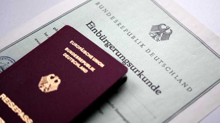 Ein deutscher Reisepass liegt auf einer Einbürgerungsurkunde.