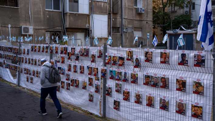 Israel, Ramat Gan: Ein Mann geht an einem Zaun mit Fotos von Geiseln vorbei