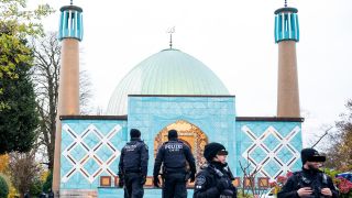 Einsatzkräfte der Polizei stehen während einer Razzia beim islamischen Zentrum Hamburg vor der Imam Ali Moschee (Blaue Moschee) (Bild: dpa / Daniel Bockwoldt)