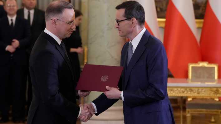 Andrzej Duda (l), Präsident von Polen, gibt Mateusz Morawiecki, Ministerpräsident von Polen, während einer Vereidigungszeremonie die Hand. Duda hat das neue Kabinett des bisherigen nationalkonservativen Ministerpräsidenten Morawiecki vereidigt.