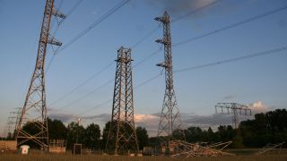 Ein Strommast im Bau steht zwischen fertigen in der Nähe von Berlin-Buch, davor liegen Bauteile des Masts (Bilöd. picture alliance / Lothar Ferstl)