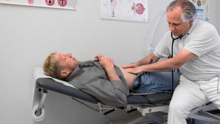 Ein Arzt untersucht den Bauch eines männlichen Patienten (Bild: Picture-Alliance/Keystona | Martin Ruetschi)