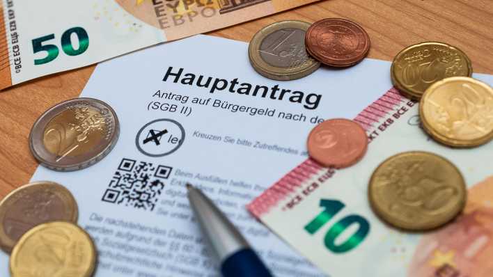 Euroscheine und -münzen liegen um einen Antrag auf Bürgergeld verteilt (Bild: picture alliance / Zoonar)