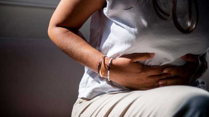 Frau mit Magenschmerzen hält sich den Unterleib