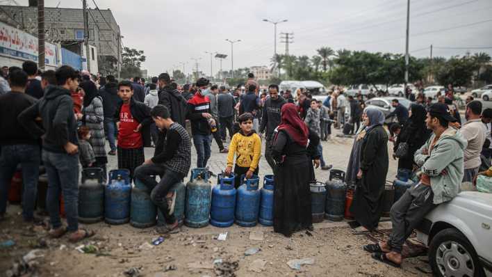 Geflüchtete Palästinenserinnen und Palästinenser warten vor einer Tankstelle auf die Ausgabe von Hilfsgütern (Bild: picture alliance / Mustafa Hassona)