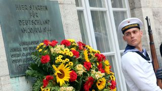 Ein Soldat des Wachbataillons der Bundeswehr steht am 20.07.2014 im Bendlerblock in Berlin neben einer Gedenktafel für die erschossenen Widerstandskämpfer des Hitler-Attentats vom 20. Juli 1944.