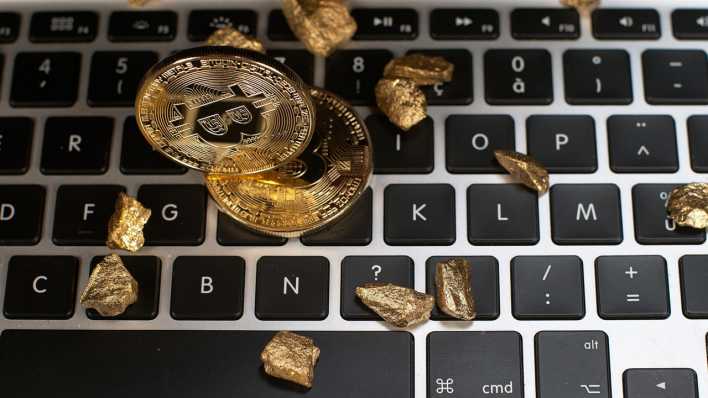 Bitcoins und Goldnuggets auf einer Computer Tastatur