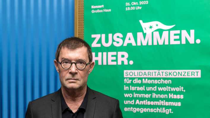 Der Intendant des Staatstheaters Cottbus, Stephan Märki, steht vor einem Plakat, auf dem zu dem Israel-Solidaritätskonzert "Zusammen hier" eingeladen wird (Bild: dpa / Frank Hammerschmidt)