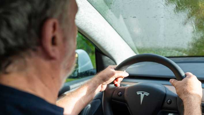 Alter Mann fährt bei Regen Auto.