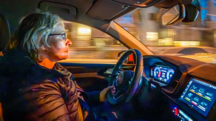 Ältere Autofahrerin fährt abends im Dunkeln in der Stadt