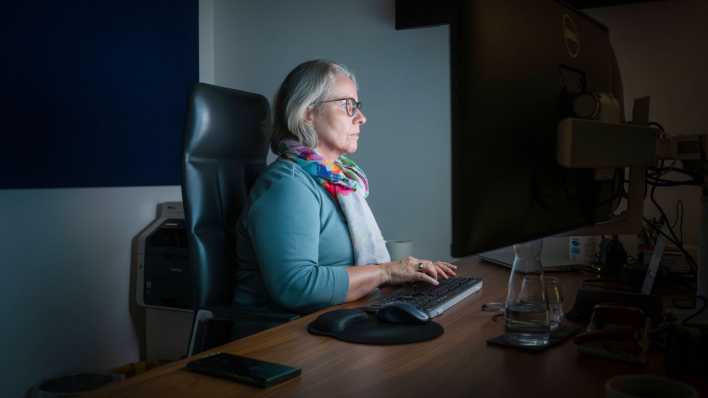 Frau arbeitet abends noch im Büro, sitzt am Computer