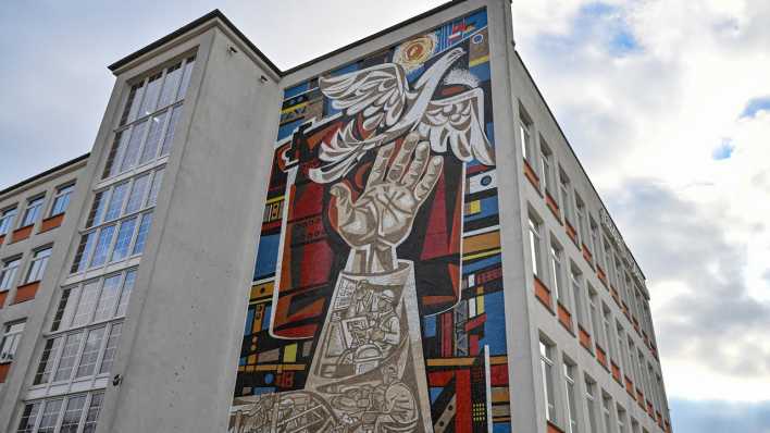 An einer Fassade in Eisenhüttenstadt ist ein großes Mosaik-Kunstwerk von Walter Womacka (1925 - 2010) zu sehen
