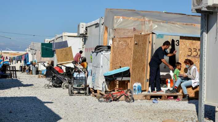 Archiv: Flüchtlinge sitzen vor Unterkünften im Flüchtlingslager Karatepe auf Lesbos.