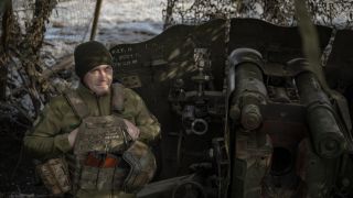 Ein ukrainischer Soldat neben einem Artillerie-Geschoss an der Front in der Ukraine.