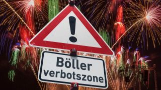 Warnschild "Gefahrstelle" und ein Zusatzschild mit der Aufschrift "Boellerverbotszone", befestigt mit roten Haltern an einem Schildermast. (Bild: picture alliance / SULUPRESS.DE | Torsten Sukrow)