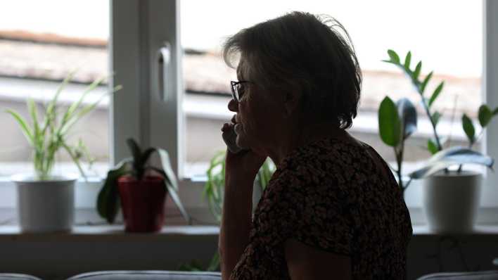 Eine Seniorin hält einen Telefonhörer ans Ohr