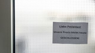 Zettel an einer Tür mit der Aufschrift: "Liebe Patienten unsere Praxis bleibt heute geschlossen"