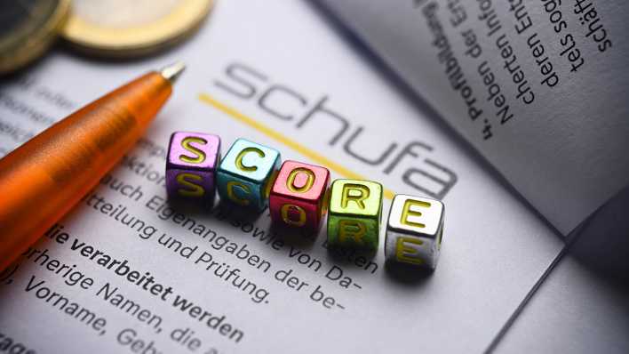 Buchstabenwürfel bilden das Wort "Score" auf einem Formular der Schufa