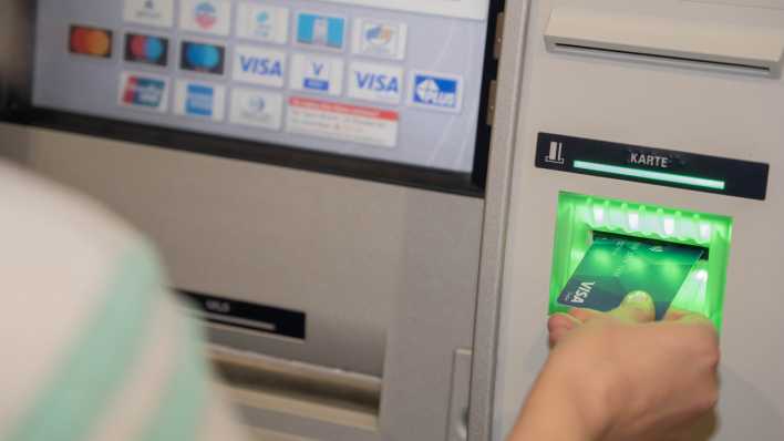 Eine Bezahlkarte wird in einen Geldautomaten eingeführt.