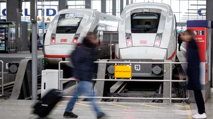 Symbolbild: Reisende gehen an geparkten ICE am Münchner Hauptbahnhof vorüber
