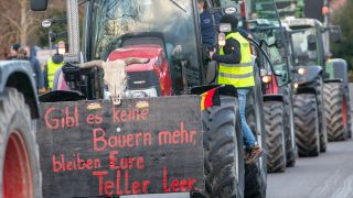 Landwirte nehmen mit ihren Treckern an einer Kundgebund Teil, auf einem Plakat steht "Gibt es keine Bauern mehr, bleiben eure Teller leer".