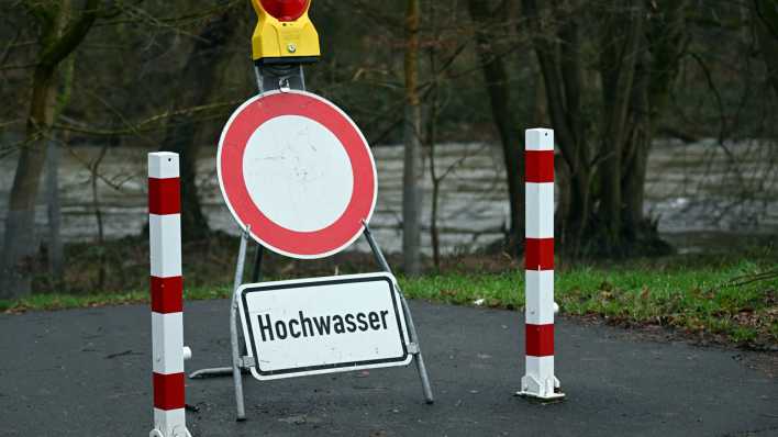 Ein Schild warnt an einem gesperrten Weg vor dem Hochwasser.