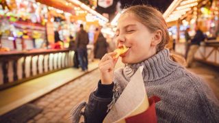 ARCHIV, München, 17.03.2020: Mädchen isst Chips auf einem Rummel (Bild: picture alliance / Westend61)