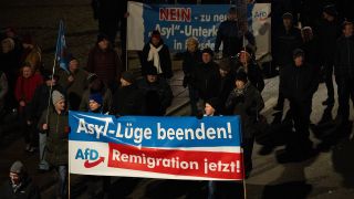 Teilnehmer einer Demonstration der Bewegung Pegida tragen Banner der AfD mit der Aufschrift "Asyl-Lüge beenden! Remigration jetzt!".