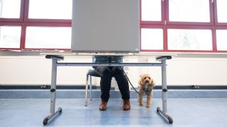 Symbolbild: Eine Frau sitzt zur Stimmabgabe in einem Wahllokal