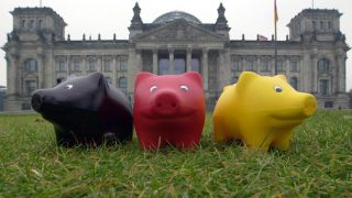 Drei Sparschweine stehen auf dem Rasen vor dem Deutschen Bundestag in Berlin und gucken in die Gegend (Bild: picture-alliance / dpa / Siewert Falko)