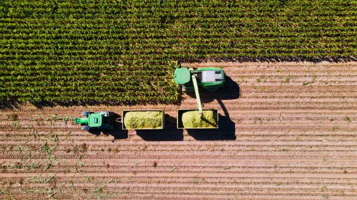 Eine Luftaufnahme eines Mähdreschers bei der Getreideernte (Bild: picture alliance / Kzenon)