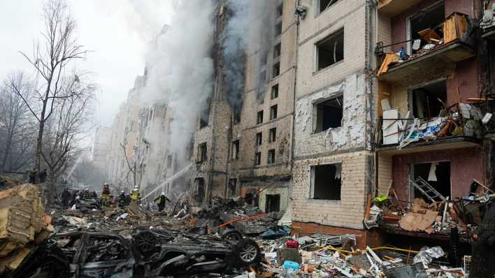 Beschädigte Autos liegen neben einem zerstörten Wohnhaus nach einem russischen Angriff.