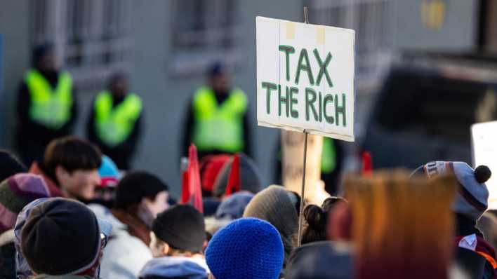 Bei einer Demonstration für Klimagerechtigkeit ist ein Schild mit der Aufschrift "Tax the Rich" zu sehen (Bild: dpa / Hannes P. Albert)