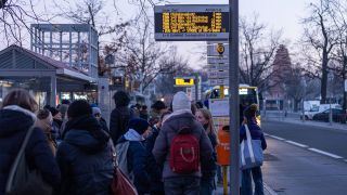 Menschen warten an einer Bushaltestelle