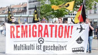 Demonstranten der identitären Bewegung mit Bannern und Transparent auf dem steht "Remigration, Multikulti ist gescheitert" (Bild: IMAGO / Deutzmann)