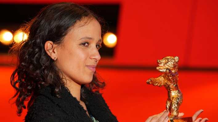 Regisseurin Mati Diop steht nach der Preisverleihung im Berlinale Palast auf dem Roten Teppich mit ihrem Goldenen Bären.