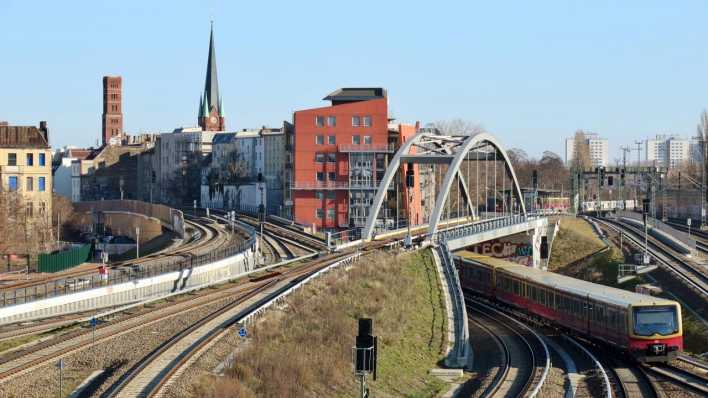 Eine S-Bahn der Linie S7 Lichtenberg fährt nahe dem Bahnhof Ostkreuz unter der Stahlbogenbrücke durch.