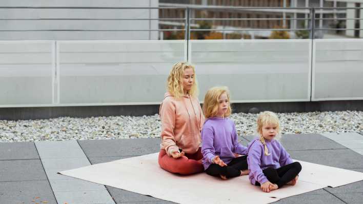 Eine Mutter und ihre Töchter meditieren.