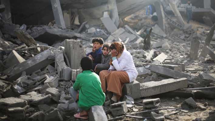 Palästinenser sitzen in Rafah auf Ruinen