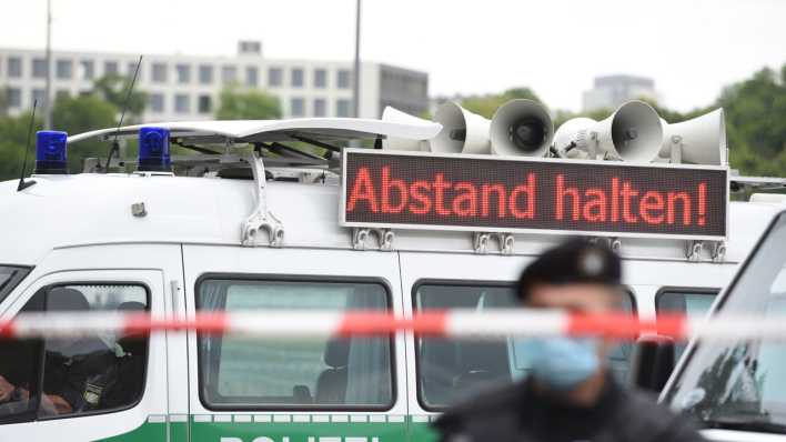 Ein Polizeiwagen mit einer Anzeige, auf der "Abstand halten!" steht.