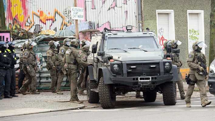 Polizisten stehen bei einem gepanzerten Fahrzeug am Markgrafendamm in Berlin
