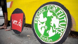 Aktivisten von Fridays for Future unterstützen vor dem BVG Betriebshof Cicerostraße die Streikenden mit Plakaten und einem gelben Bus aus Pappe, auf den selbstgemalte Logos von Verdi und Fridays For Future geklebt.