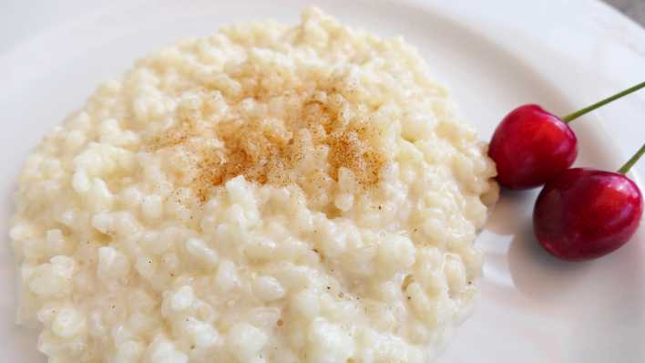 Milchreis mit Zimtzucker bestreut und zwei Kirschen garniert (Bild: picture alliance/Martina Raedlein)